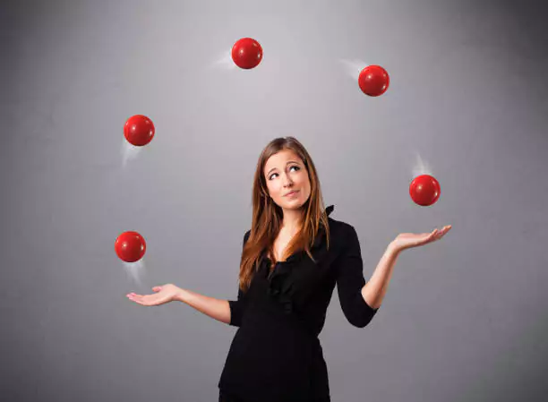 Красивая молодая девушка стоит и жонглирует красными мячами