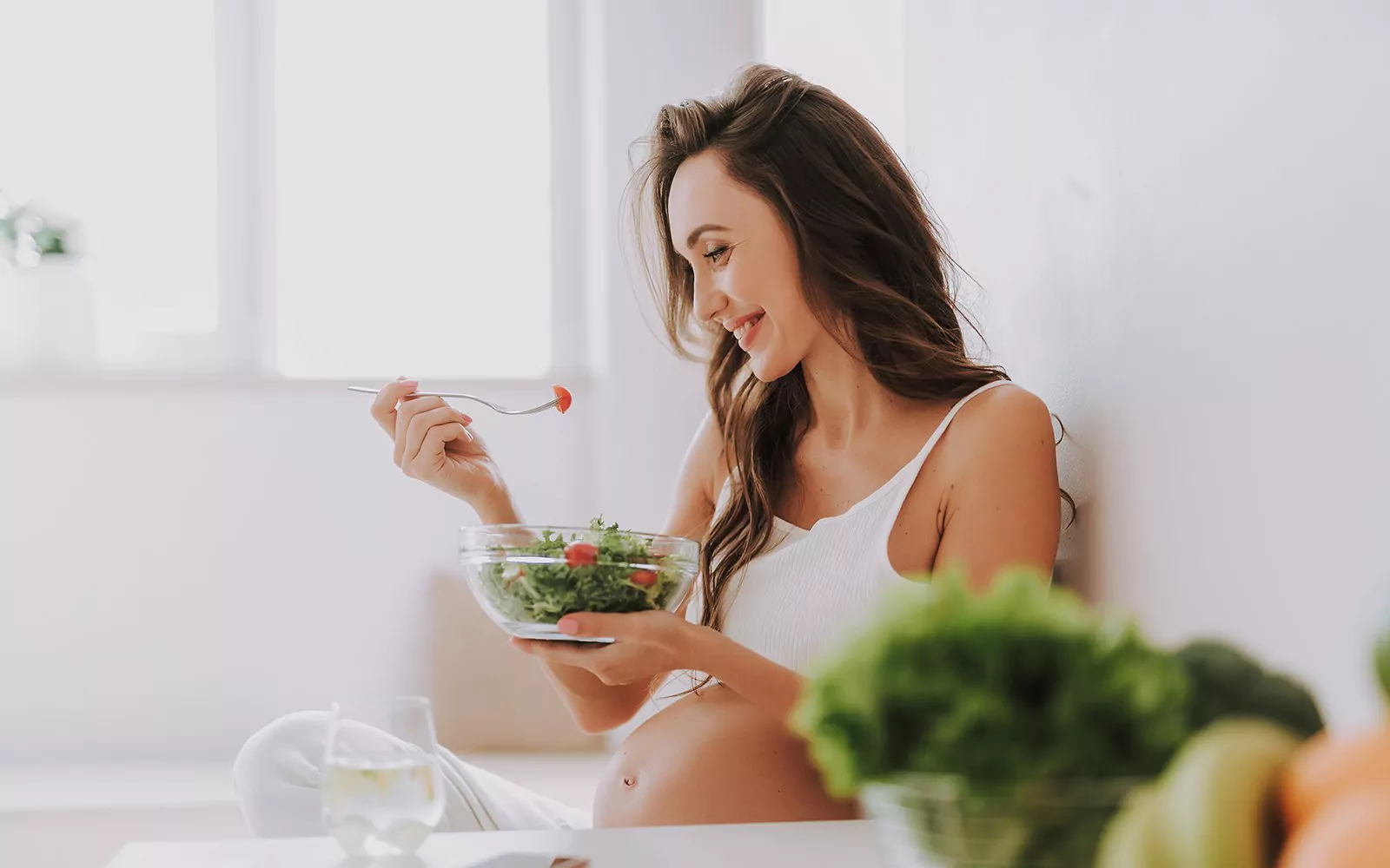 Беременная девушка ест салат 